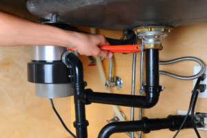 Close Up Of A Plumber's Hand Repairing Under the Sink Garbage Disposal Unit