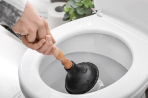 Homeowner Holding Plunger to Repair Toilet