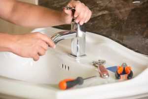 Homeowner Attempting Repair of Bathroom Sink Faucet with Tools