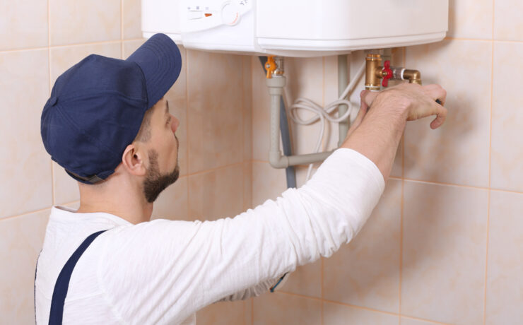 Plumber Repairing a Faulty Water Heater in a Bathroom