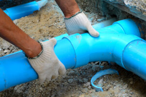 Plumber's Gloved Hands Holding Newly Installed Sewer Line Replacement