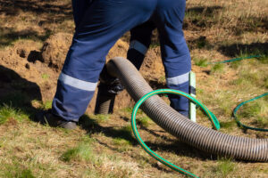 Professional Plumber Inserting Flexible Pipe into Ground During Sewage Pump Installation