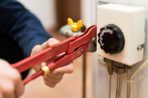 Plumber Holding Wrench and Repairing Water Heater
