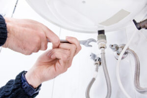 Close Up of a Person’s Hands While Repairing a Water Heater